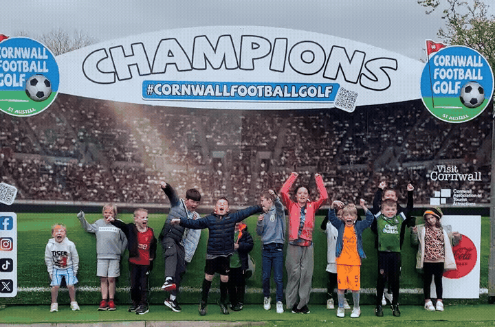 Children Jumping around in front of the Champions Sign